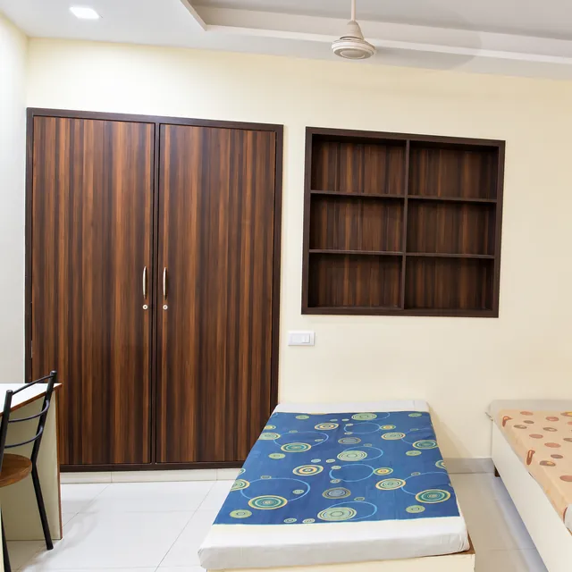 Bedroom with wardrobe, wall shelves and individual beds