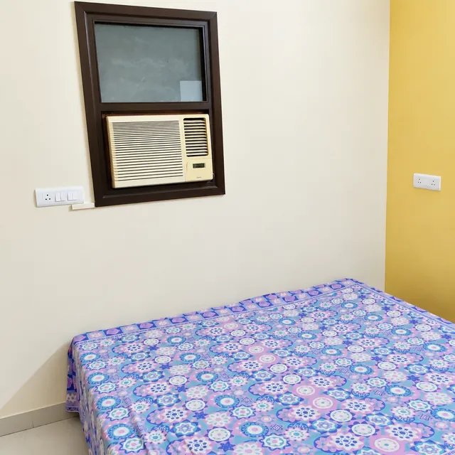 Bedroom with window air conditioning and patterned bedding